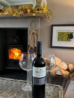 a bottle of wine sitting on a table with two glasses at Borders Escape with Hot Tub in West Linton