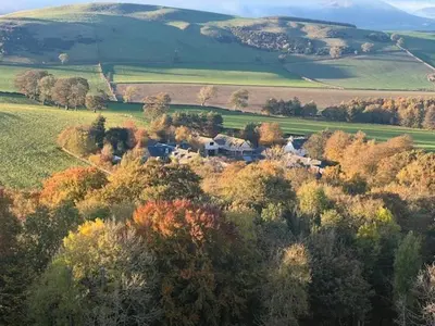 a house in the middle of a field with trees at Borders Escape with Hot Tub in West Linton