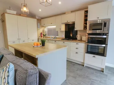 a kitchen with white cabinets and a wooden counter top at Serenity Lodge in Wemyss Bay
