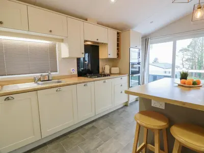 a kitchen with white cabinets and a large window at Serenity Lodge in Wemyss Bay