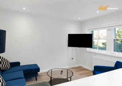 a living room with blue chairs and a flat screen tv at Comfy 1 Bed Airdrie Flat w Private Parking in Airdrie