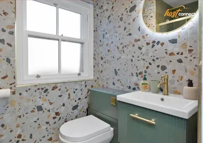 a bathroom with a toilet and a sink and a window at Comfy 1 Bed Airdrie Flat w Private Parking in Airdrie