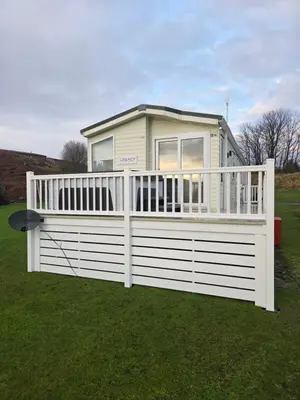 a house with a white fence in the grass at Noah's Luxe Retreats in Newton Stewart