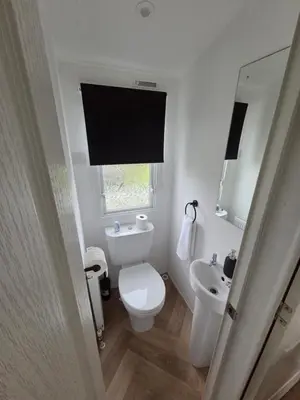 a white bathroom with a toilet and a sink at Noah's Luxe Retreats in Newton Stewart