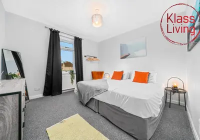 a bedroom with a large bed with orange pillows at Mc Culloch Apartment by Klass Living Viewpark in Uddingston