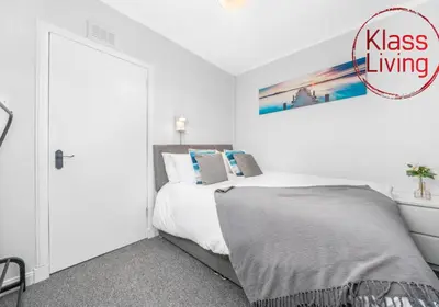 a white bedroom with a bed and a painting on the wall at Mc Culloch Apartment by Klass Living Viewpark in Uddingston