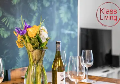 a bottle of wine and a vase of flowers on a table at Mc Culloch Apartment by Klass Living Viewpark in Uddingston
