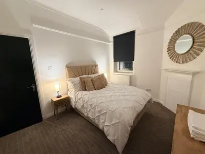 a bedroom with a bed with a mirror and a lamp at The perfect place we call home in Dumbarton