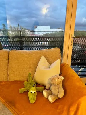 three stuffed animals sitting on a couch with a window at Skyline Serenity Cost Flat in Glasgow