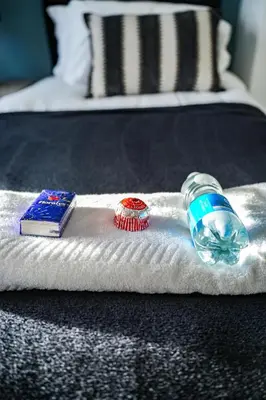 a towel with a toothbrush and a bottle on a bed at Elm House in Bathgate
