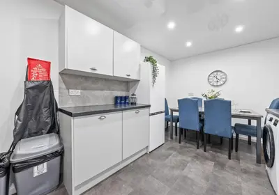 a kitchen with white cabinets and a table with blue chairs at Elmbank Avenue House by Klass Living Uddingston in Uddingston