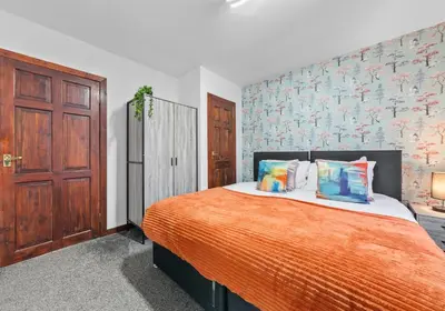 a bedroom with a large bed with an orange blanket at Elmbank Avenue House by Klass Living Uddingston in Uddingston