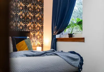 a bedroom with a bed and a window with blue curtains at Elmbank Avenue House by Klass Living Uddingston in Uddingston