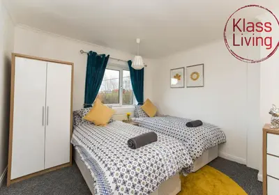 two beds in a bedroom with blue curtains at Kenmar House by Klass Living Hamilton in Hamilton