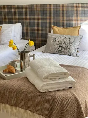 a bed with a tray with towels and flowers on it at Keeper's Cottage at Slogarie Estate in Castle Douglas
