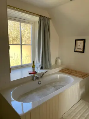 a large bath tub in a bathroom with a window at Keeper's Cottage at Slogarie Estate in Castle Douglas