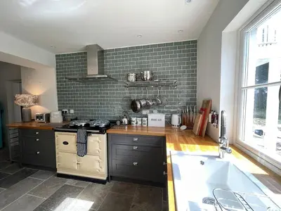 a kitchen with black cabinets and a sink and a tub at Keeper's Cottage at Slogarie Estate in Castle Douglas