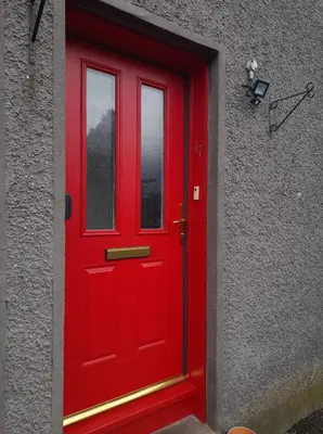 a red door on the side of a building at Celia's house in Stirling