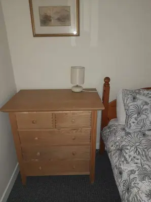 a wooden dresser with a lamp on top of it next to a bed at Celia's house in Stirling