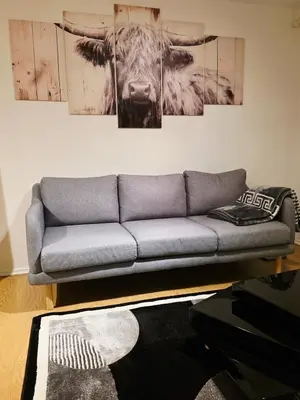 a couch in a living room with a cow on the wall at Cozy 2Bed Flat in Glasgow City Center in Glasgow