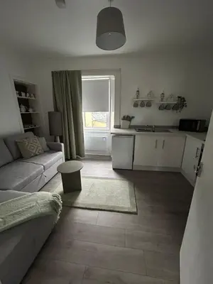 a living room with a couch and a kitchen at Calm of Cumbrae in Millport