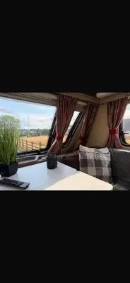 a room with a couch and a table with a window at 4 berth caravan in Doune