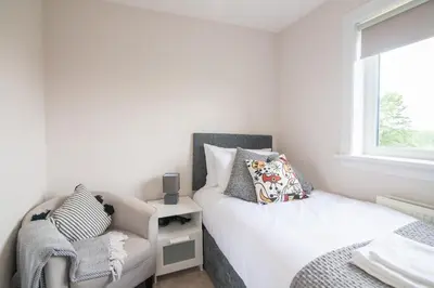 a bedroom with a bed and a chair and a window at Stylish Stirling home with stunning views in Stirling