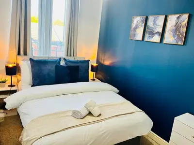 a blue bedroom with a bed with two towels on it at 3-Bedroom house near Manchester City Centre in Moffat