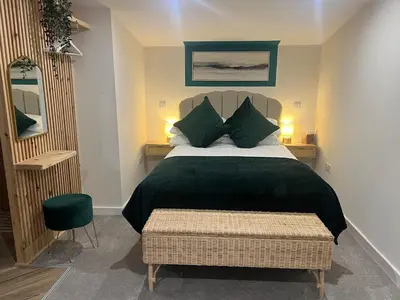 a bedroom with a bed with a black blanket and green pillows at The Wee Bank Hut in Oban