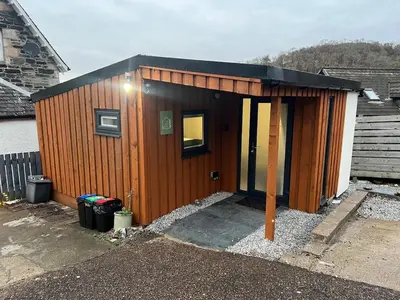 a small wooden house with a black roof at The Wee Bank Hut in Oban