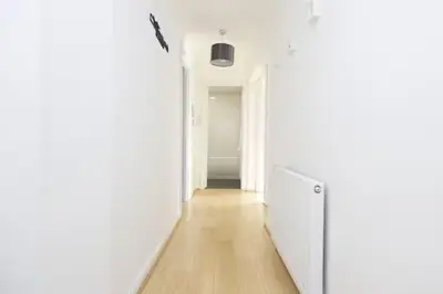 a hallway with white walls and a wooden floor at Bright 3 Bed Apt overlooking the Clyde SEC & Hydro in Glasgow
