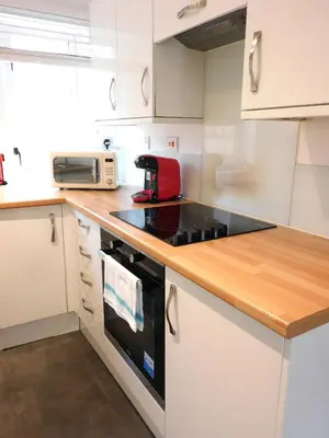 a kitchen with white cabinets and a stove top oven at Bright 3 Bed Apt overlooking the Clyde SEC & Hydro in Glasgow