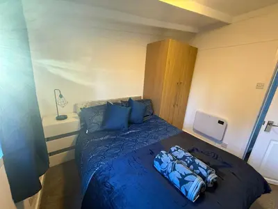 a bedroom with a large bed with blue sheets at Bethany Woodland Lodge in Winchburgh