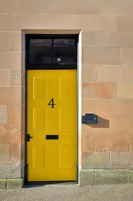 a yellow door with the number four on a brick wall at No 4 Burnbank in Oban