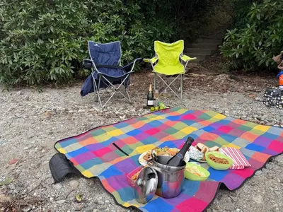 a picnic blanket with a table and two chairs and a bottle of wine at 6 Lomond Castle - The Inchcruin Suite in Luss