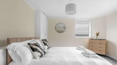 a bedroom with a bed with white sheets and a mirror at Craigend Cottage in Rothesay