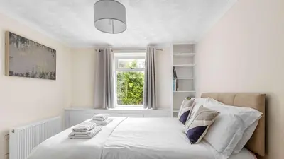 a white bedroom with a bed with a window at Craigend Cottage in Rothesay