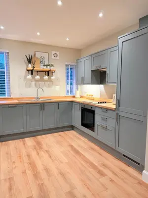 a kitchen with gray cabinets and a wooden floor at Bright and spacious 2 bedroom flat in Auchterarder