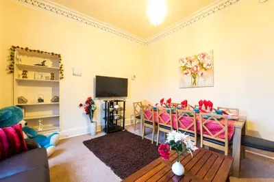 a living room with pink chairs and a tv at Edinburgh Central Morrison Roomz in Edinburgh