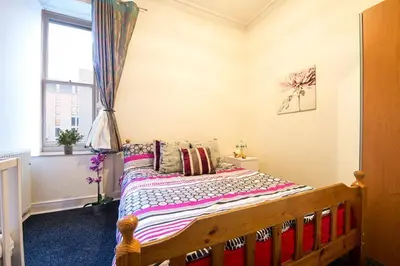a bedroom with a wooden bed with a window at Edinburgh Central Morrison Roomz in Edinburgh