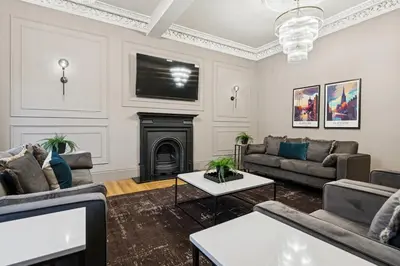 a living room with couches and a fireplace at Spacious 5 Bedroom Home With 3 Bathrooms And Private Parking in Glasgow