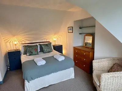 a bedroom with a bed and a dresser and a mirror at Curlew Cottage - Peaceful Setting Stunning Views in Bruichladdich