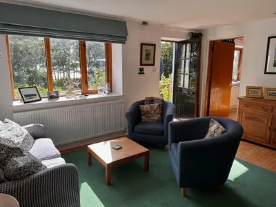 a living room with two chairs and a table at Curlew Cottage - Peaceful Setting Stunning Views in Bruichladdich