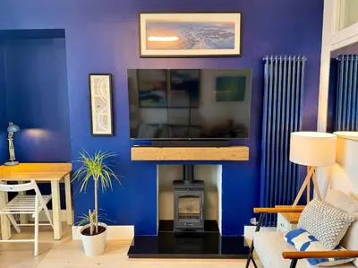 a living room with a blue wall with a fireplace at Warm upgraded top-floor flat in Finnieston in Glasgow