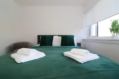 a bedroom with a green bed with two towels on it at Signature - Duncan House in Wishaw