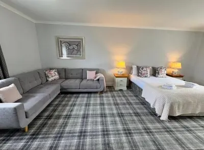 a living room with a couch and a bed at Belstane Manor in Carluke