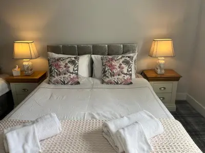 a bedroom with a large bed with two lamps at Belstane Manor in Carluke