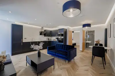 a living room with a blue couch and a kitchen at Old Church Apartment 2 in Oban