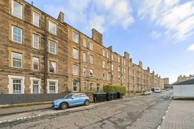 a blue car parked in front of a brick building at City-Close 1-Bedroom Apartment - Edinburgh in Edinburgh