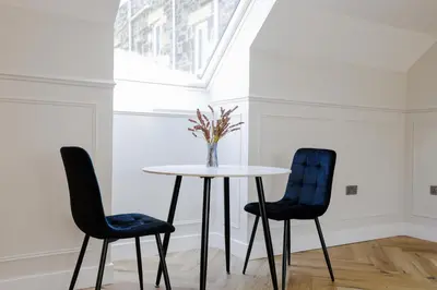 a table with two chairs and a vase with flowers at Old Church Apartment 4 in Oban